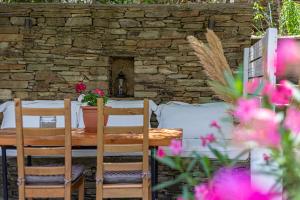 a wooden table with chairs and a stone wall at Small Paradise in Andros