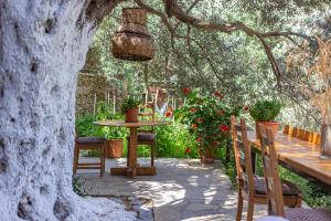 a patio with a table and chairs under a tree at Small Paradise in Andros
