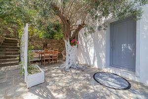 a tree next to a house with a table and a door at Small Paradise in Andros