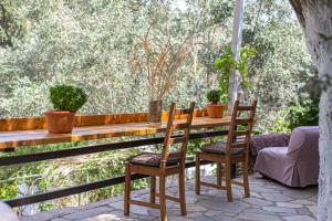 a wooden table and chairs on a porch with plants at Small Paradise in Andros
