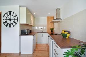 una cocina con armarios blancos y un reloj en la pared en The Cow Shed at Quex Park Estate, en Birchington