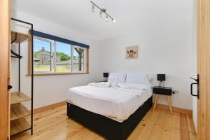 a white bedroom with a bed and a window at The Cow Shed at Quex Park Estate in Birchington