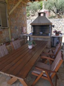 a wooden picnic table and chairs in front of a fireplace at Riza Apartments in Kardamili
