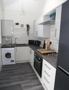 a white kitchen with a sink and a dishwasher at Cheerful 4-bedroom home in Sheffield in Walkley