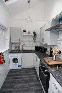 a kitchen with white cabinets and a washer and dryer at Cheerful 4-bedroom home in Sheffield in Walkley