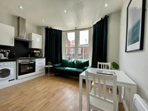 Il dispose d'une cuisine et d'un salon avec une table et un canapé vert. dans l'établissement 1 Bed 2 Person Apartment City Centre, à Cardiff