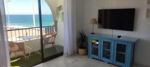 sala de estar con TV y balcón con vistas a la playa en Al-Ándalus Suite Tropical en Almuñécar