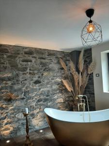 uma banheira na casa de banho com uma parede de pedra em Suite Onorio B&B Zia Vivina em Sorico