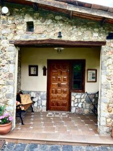 Casa de piedra con puerta de madera y banco en Casa el Frances, en Candamin