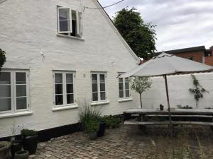 a white house with a table and an umbrella at Rebslagerhuset in Ribe