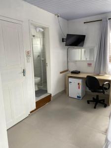 a room with a desk and a chair and a bathroom at Hotel Nunes in Curitiba