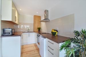- une cuisine avec des placards blancs et des comptoirs en bois dans l'établissement The Piggery, Quex Park Estate, à Birchington