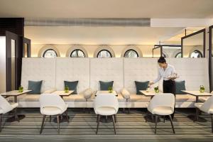 a chef standing in a restaurant with a plate of food at COMO The Halkin in London