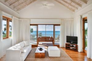 a living room with a white couch and a television at COMO Parrot Cay in Sandy Point