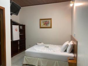 um pequeno quarto com uma cama com lençóis brancos em Aquarius Hotel Aquarius em Ariquemes