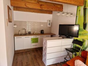 a kitchen with white cabinets and a flat screen tv at Domek Pattie in Giżycko