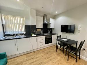 een keuken met witte kasten en een zwarte tafel en stoelen bij One Bedroom Apartment In City Centre in Cardiff