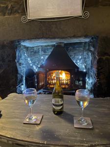 a bottle of wine and two glasses on a table with a fireplace at 3 bedroom cottage Tremadog square porthmadog in Tremadoc