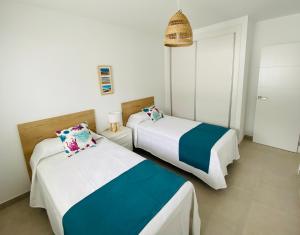 two beds in a room with white and blue at Puerto del Carmen, CASA MAMÁ in Puerto del Carmen