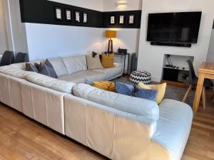 a living room with a large couch and a television at Temperance House in Burnham-on-Crouch