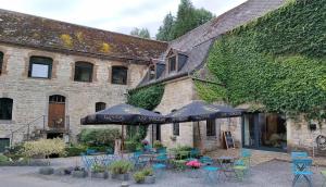 ein Gebäude mit Tischen, Stühlen und Sonnenschirmen in der Unterkunft Hotel Le Moulin Des Ramiers in Crupet