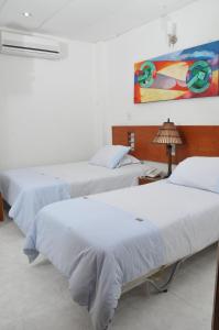 a bedroom with two beds and a painting on the wall at Hotel Barrancabermeja Plaza in Barrancabermeja