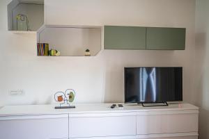 a kitchen with white cabinets and a flat screen tv at Vicolo delle Forbici in Città della Pieve