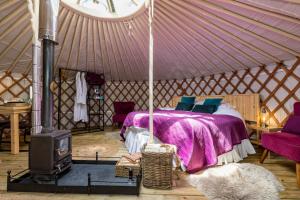 a bedroom with a bed and a stove in a yurt at Yurt with Hot Tub near Hartington, Peak District in Buxton