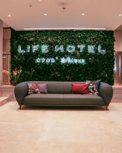 um sofá sentado em frente a uma parede verde em Life Hotel em Bibione