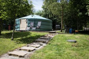 a green tent with two chairs and a path leading to it at Yurt with Hot Tub near Hartington, Peak District in Buxton