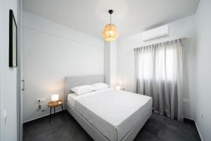 een witte slaapkamer met een bed en een raam bij The H Experience Blackbird Spacious 2BD Apartment close to the beach in Xylokastron