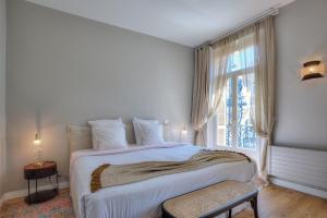a white bedroom with a large bed and a window at Maison Lamartine - Nice in Nice