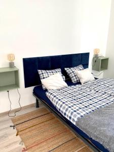 ein blaues Bett mit Kissen darauf in einem Zimmer in der Unterkunft Apartman 001 in Bük