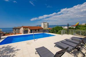 a swimming pool with lounge chairs on a patio at Apartments Vila Belvedere in Rijeka