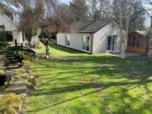 a small white house in a yard with a tree at Chase Bungalow in Billericay