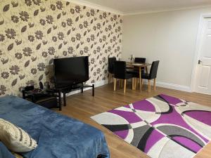 a living room with a tv and a table with chairs at Chase Bungalow in Billericay