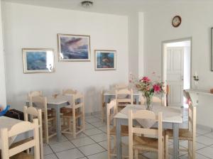 una sala da pranzo con tavoli e sedie con fiori di King Thiras Hotel a Firà
