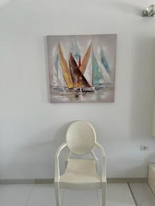 a white chair in front of a painting of sailboats at Apartman Priko 63A in Mali Lošinj