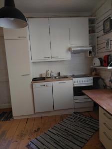 uma cozinha com armários brancos, um lavatório e um fogão em Jõevaara Veskitalu 