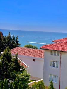 a white building with a red roof and the ocean at Апартамент Свети Влас in Sveti Vlas