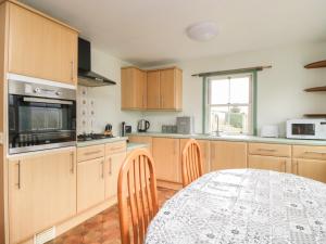 a kitchen with wooden cabinets and a table with chairs at Shaw Cottage in Dumfries