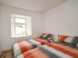 two beds in a white room with a window at Shaw Cottage in Dumfries