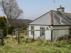 a small white house on a hill in a field at Shaw Cottage in Dumfries