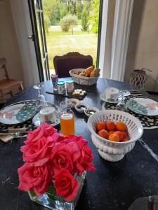 a table with flowers and bowls of fruit on it at La Sellerie in Romagné +15 photos