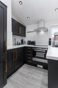a kitchen with black cabinets and white counter tops at Air Host and Stay - Beautiful modern Rodney Street apartment in Liverpool