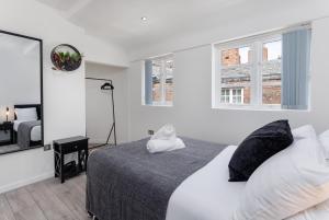 a white bedroom with a bed and two windows at Air Host and Stay - Beautiful modern Rodney Street apartment in Liverpool