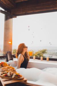 a woman sitting in front of a table with food at Karma Suites Cappadocia in Uchisar