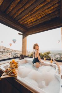 a woman sitting in a bath tub with a view at Karma Suites Cappadocia in Uchisar