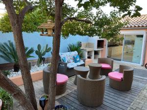 eine Terrasse mit Stühlen, einem Sofa und einem Baum in der Unterkunft Haut de villa très bien équipé avec jardin, piscine, proche centre ville Sanary in Sanary-sur-Mer