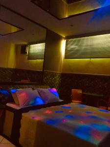 Impérium Inn Motel (Adult Only) في Nova Ponte: غرفة نوم مع سرير مع أضواء زرقاء وأرجوانية